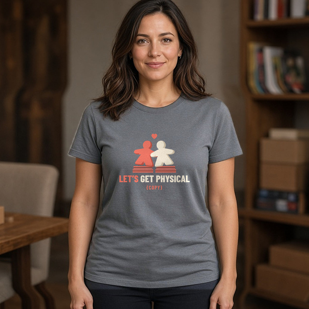 Woman wearing a charcoal t-shirt printed with two meeples sharing a heart (spicy version). Model image is digitally generated. The print shown is the actual design; colours and fit may vary slightly, see size chart.