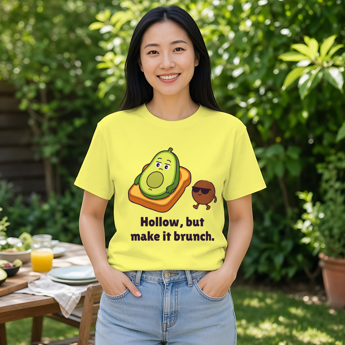 Woman with long black hair wearing the cornsilk yellow Existential Avocado tee at a backyard brunch table
