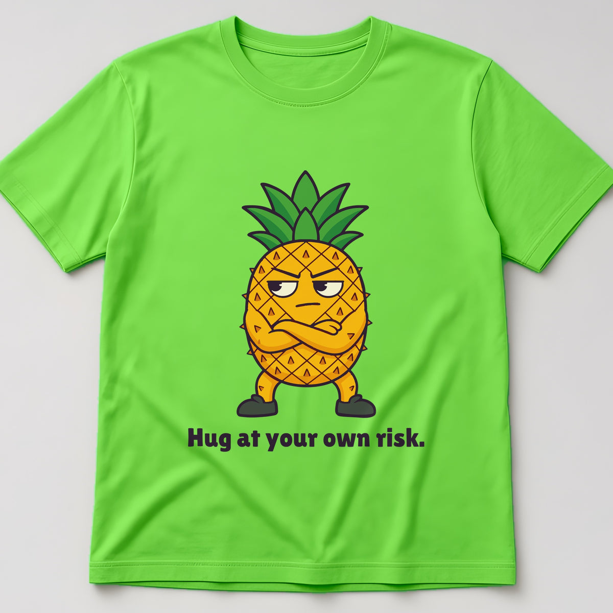 Lime t-shirt, flat lay, printed with a pineapple with its arms crossed and the words 'Hug at your own risk.'