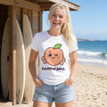 Woman with a blonde ponytail wearing the white Winking Peach tee at the beach