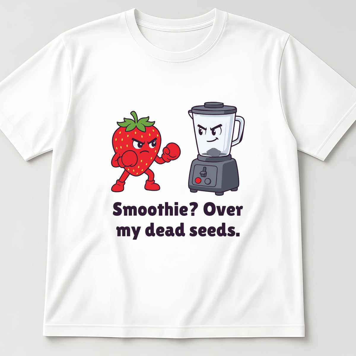 White t-shirt, flat lay, printed with a strawberry with its fists up facing a blender and the words 'Smoothie? Over my dead seeds.'