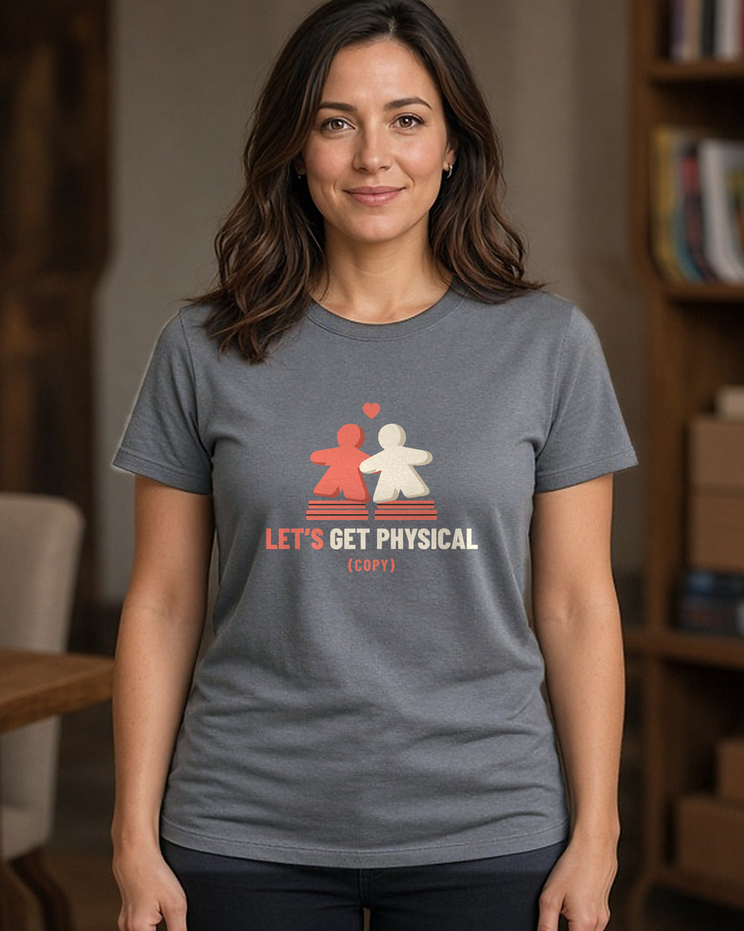 Woman wearing a charcoal t-shirt printed with two meeples sharing a heart (spicy version) (4:5 crop). Model image is digitally generated. The print shown is the actual design; colours and fit may vary slightly, see size chart.