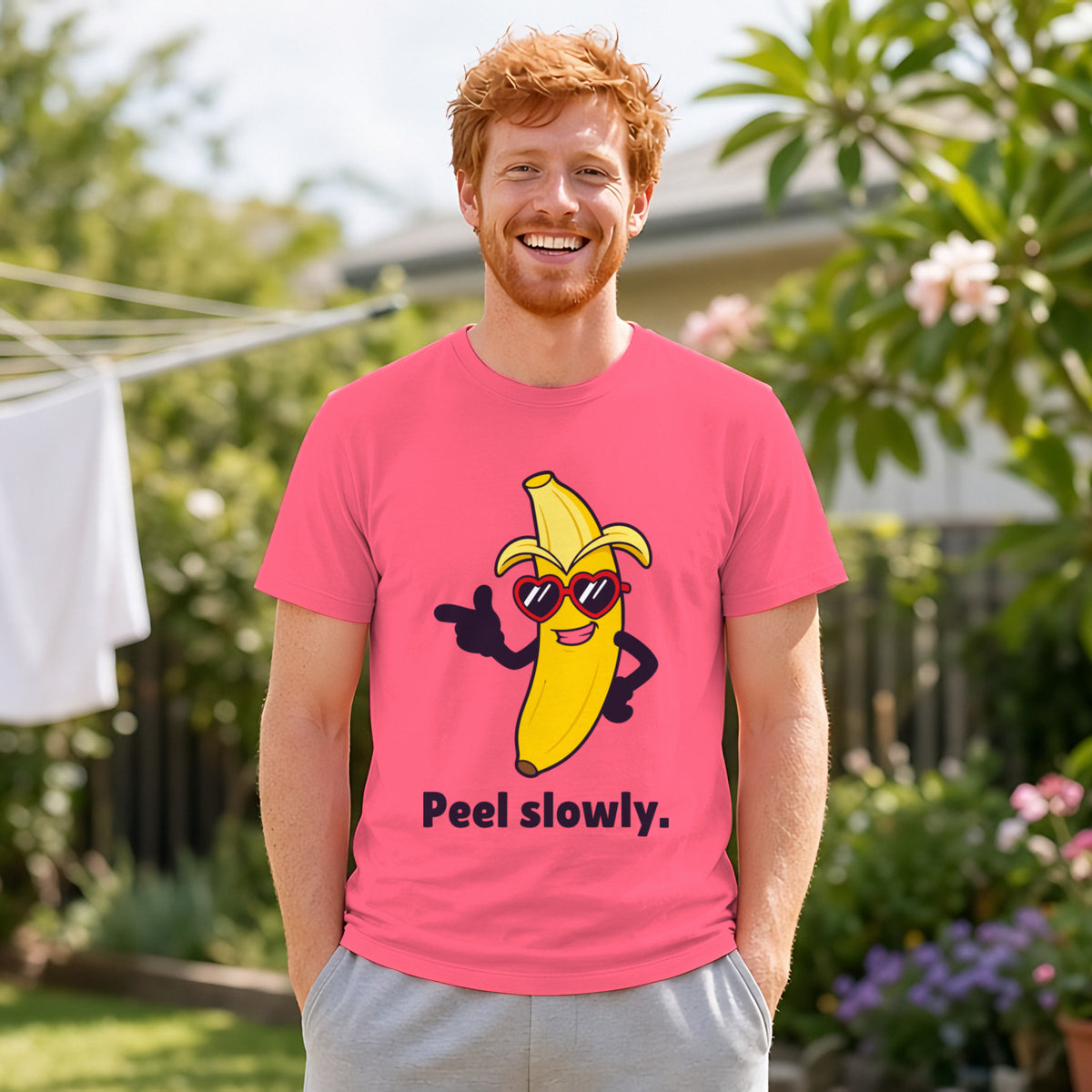 Man with ginger hair and a short beard wearing the coral pink Suave Banana tee in a backyard