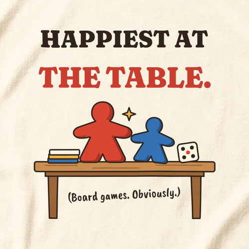 Close-up of the clean version print 'Happiest at the table. (Board games. Obviously.)' on a natural t-shirt