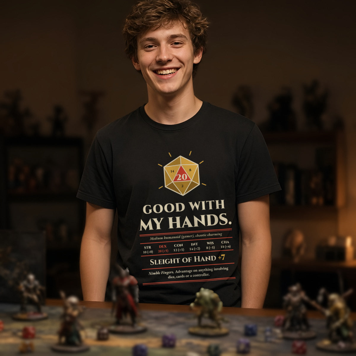 Man wearing a black t-shirt printed with 'Good with my hands. Sleight of Hand +7' (Spicy version), at a tabletop RPG table. Model image is digitally generated. The print shown is the actual design; colours and fit may vary slightly, see size chart.