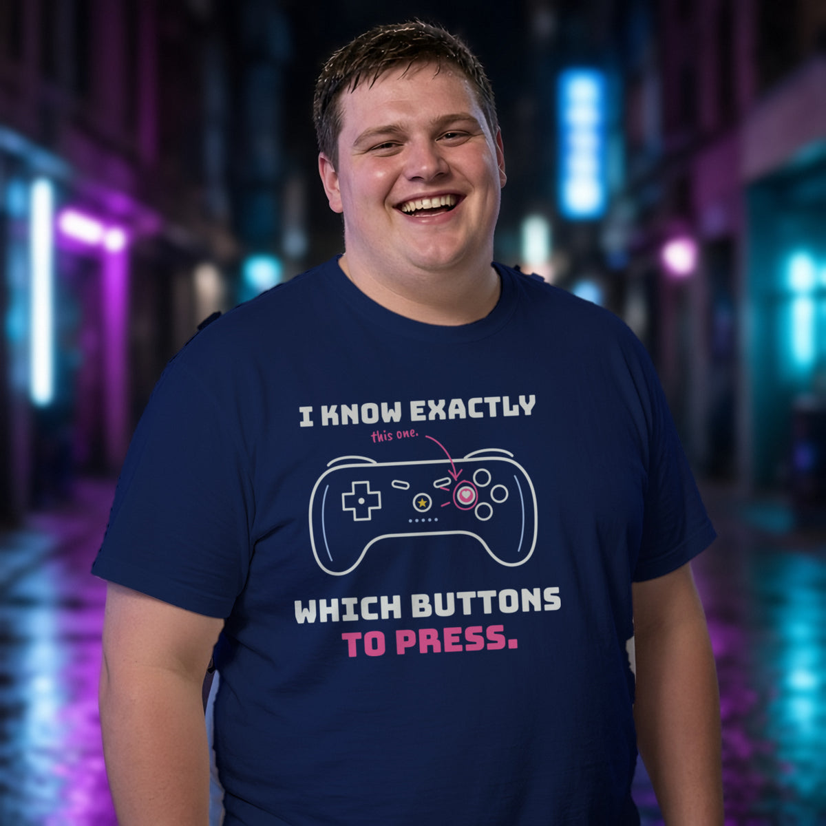 Man wearing a navy t-shirt printed with 'I know exactly which buttons to press.' (Spicy version), in a neon-lit laneway. Model image is digitally generated. The print shown is the actual design; colours and fit may vary slightly, see size chart.