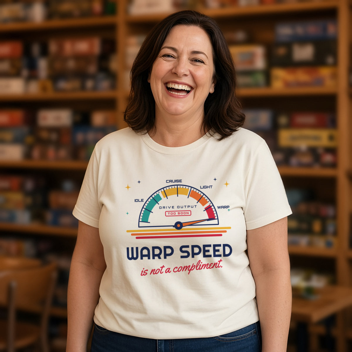 Woman wearing a natural t-shirt printed with 'Warp speed is not a compliment.' (Spicy version), in a board game cafe. Model image is digitally generated. The print shown is the actual design; colours and fit may vary slightly, see size chart.