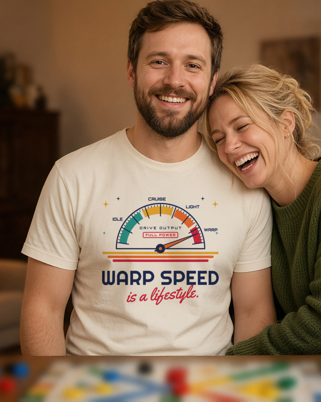 Man wearing a natural t-shirt printed with 'Warp speed is a lifestyle.' (clean version), at a board game night (4:5 crop). Colours and fit may vary slightly, see size chart.