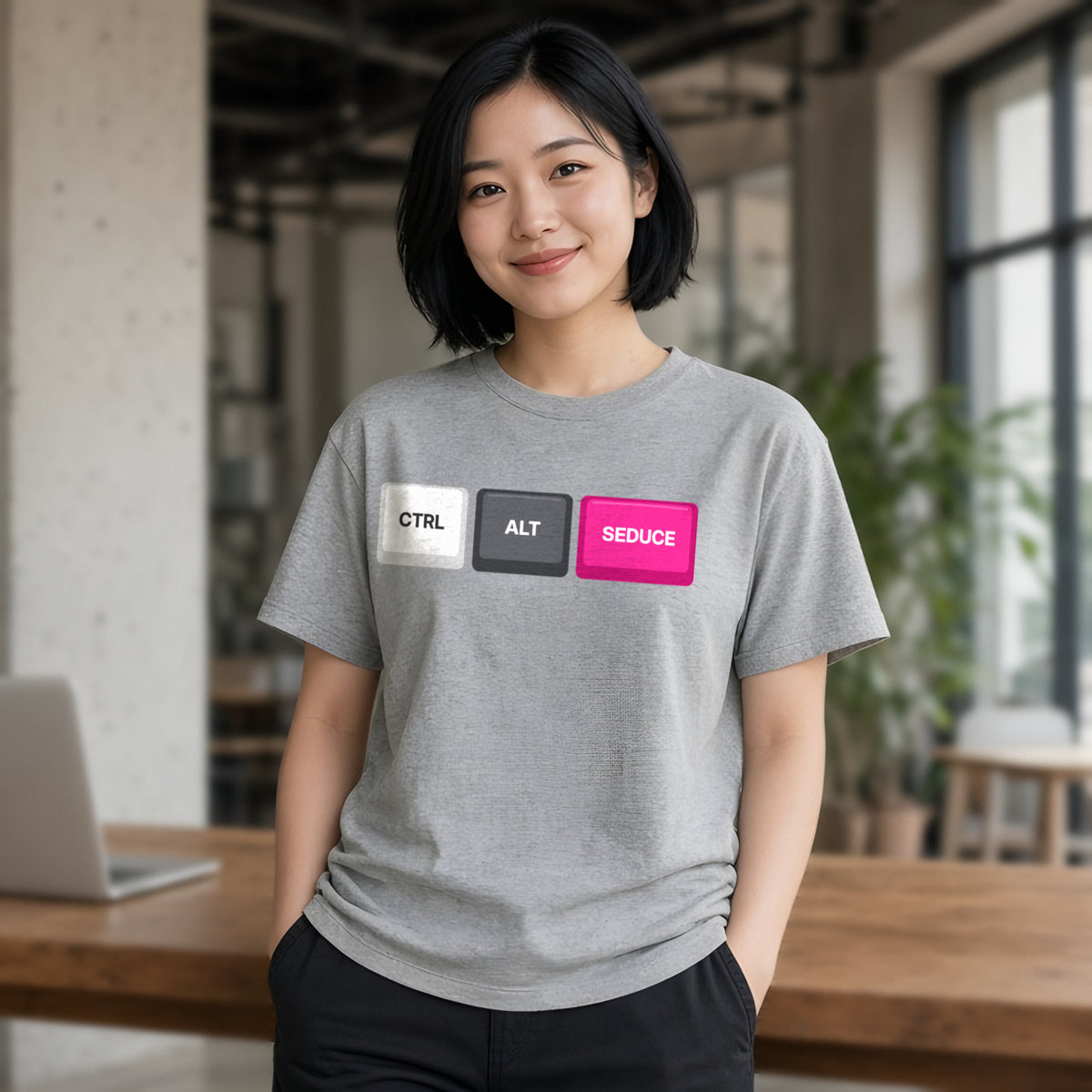 Woman wearing a sport grey t-shirt printed with Ctrl Alt Seduce keycaps (Spicy version), in a cafe. Model image is digitally generated. The print shown is the actual design; colours and fit may vary slightly, see size chart.